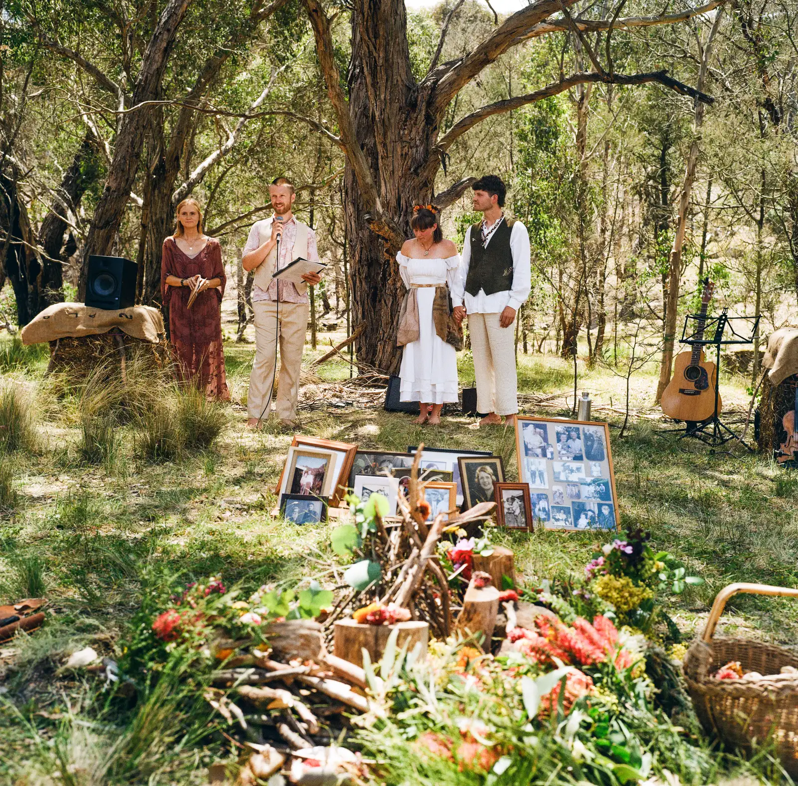 Tom Allen officiating an intimate bush ceremony among Australian eucalyptus trees, with photographs and natural decorations laid out in the foreground